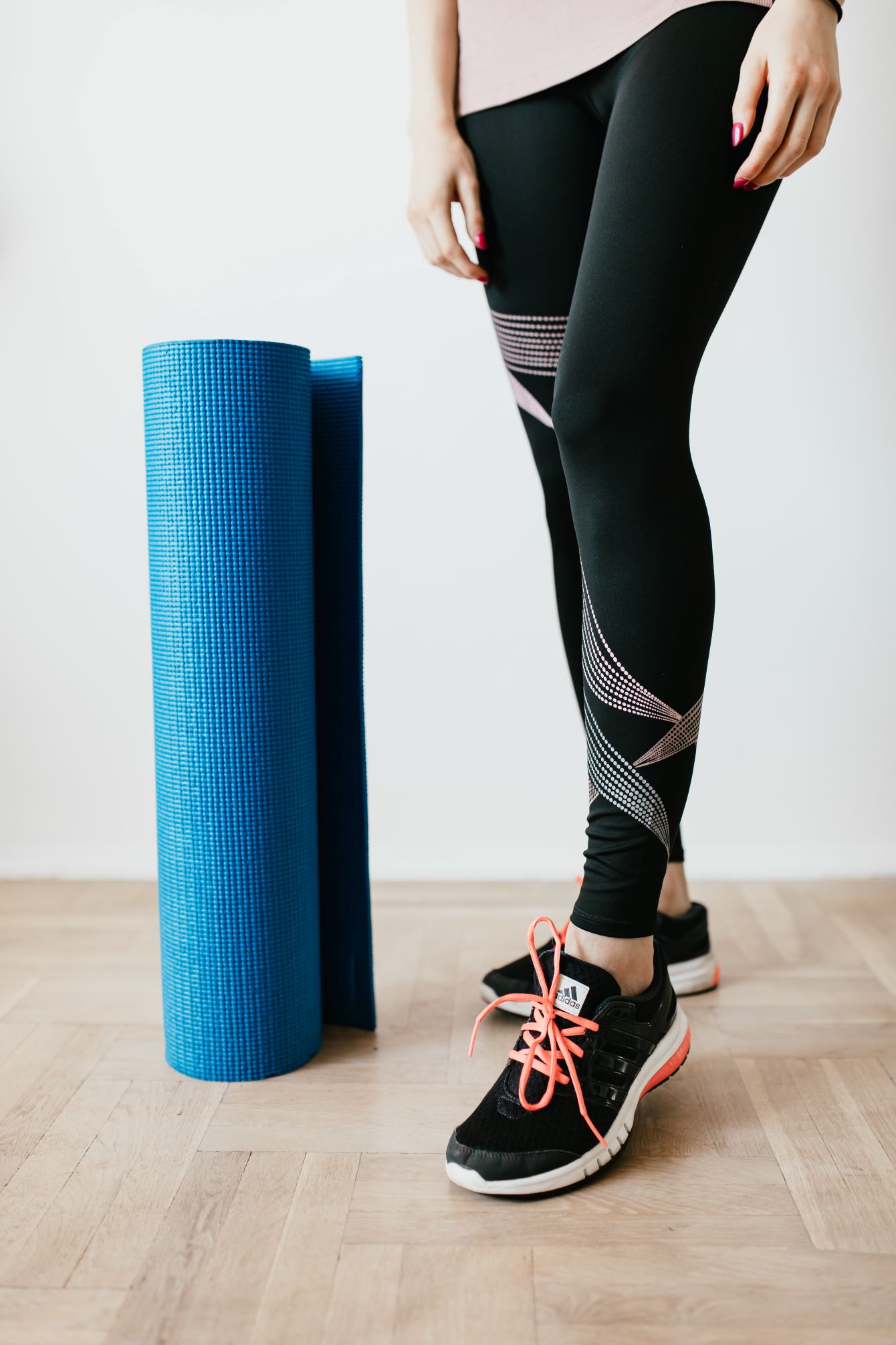 Woman standing next to yoga mat in activewear