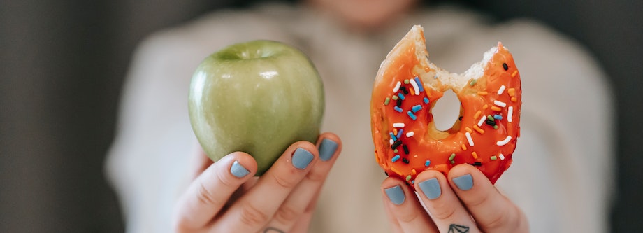 Person holding apple and doughnut